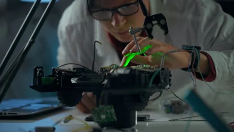 Technician assembling a robotic vehicle in a laboratory during evening hours Stock Footage 289572754