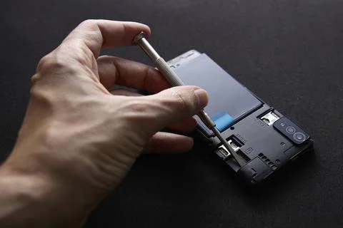 Technician assembling smartphone using screwdriver mobile repair closeup Stock Photos