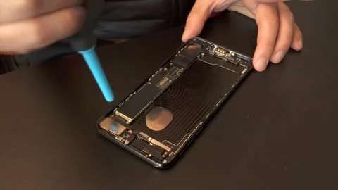 Technician blows dust off while repairing cellular phone - 4K Stock Footage 295004501