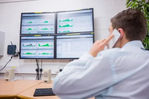 Technician calling and looking at computer screen Stock Photos