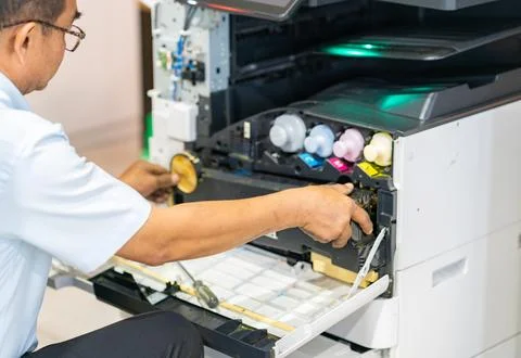 Technician carefully installing or removing a waste toner box inside an off.. 스톡 사진