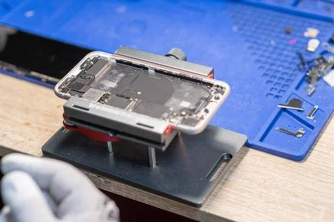 A technician carefully works on a smartphone to replace its battery in a de.. Stock Photos