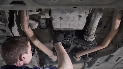 Technician carries out diagnostics and repair under body car Stock Footage 75320397