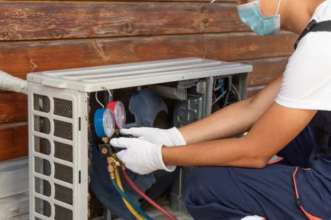 Technician is checking a air conditioner. Worker wearing a disposable protect Stock Photos