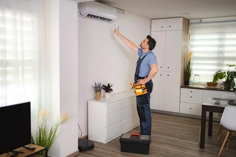 Technician checking air conditioning temperature with infrared thermometer in a Stock Photos