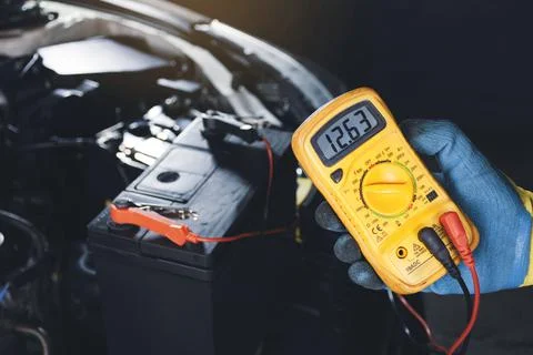 Technician checking car battery voltage with digital multimeter Stock Photos