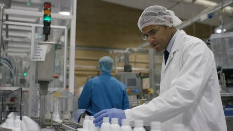 Technician checking cosmetic bottles on production line in factory Stock Footage 107972342