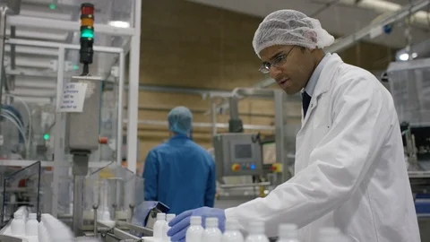 Technician checking cosmetic bottles on production line in factory Stock Footage 107972345