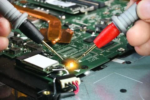 Technician checking electronics part on circuit board with probe of multimeter Foto stock