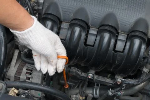 Technician is checking engine oil level of car, oil stick in the car Stock Photos