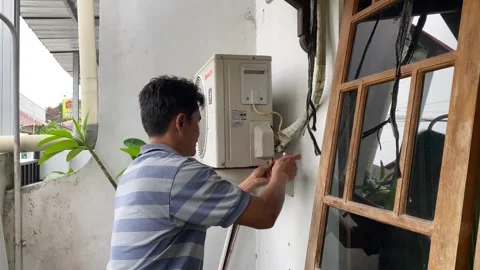 A technician is checking the outdoor unit of an air conditioner Stock Footage 347544425