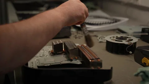Technician cleaning cooling system of video game console using brush, ensuring Stock Footage 310619796