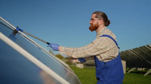Technician cleaning solar panel with brush and protective gloves Stock Footage 314406401