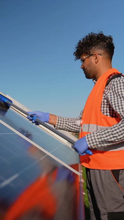 Technician cleaning solar panels for efficient renewable energy Stock Footage 314410619