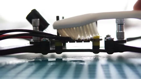 Technician cleans FPV drone board with brush. Stock Footage 317997624