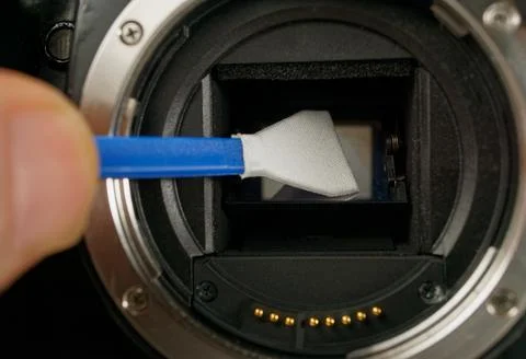 Technician cleans sensor of digital camera from dust and dirt Stock Photos