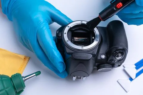 The technician cleans the sensor of the DSLR camera with a brush Stock Photos