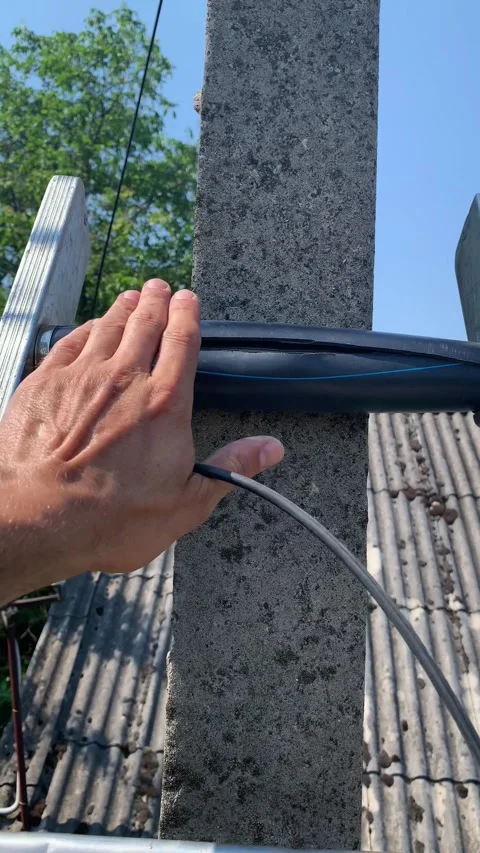 Technician climbs pole with ladder to install fiber optic cable for subscriber Video stock 346298769