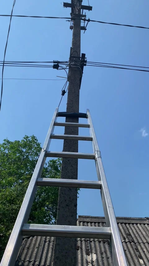 Technician climbs pole with ladder to install fiber optic cable for subscriber Video stock 346298771