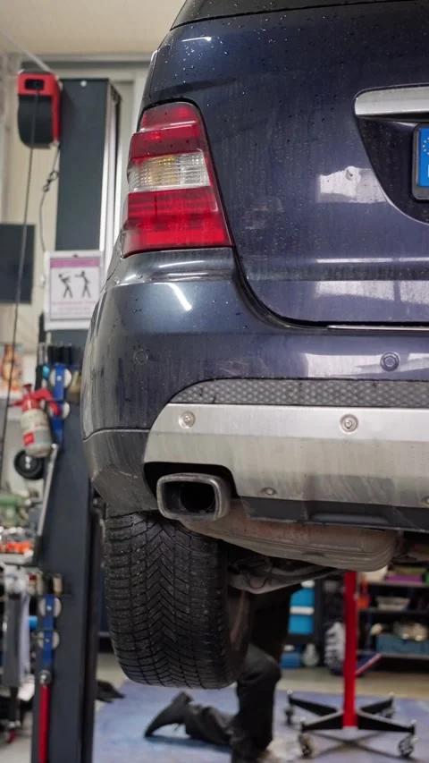 Technician conducting maintenance on underside of vehicle using equipment and Stock Footage 322170848