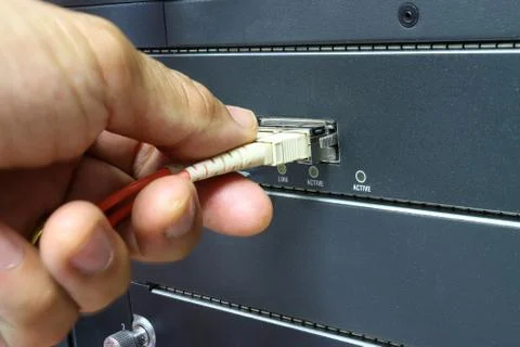 Technician connect fiber cable network to switch port in server room Stock Photos