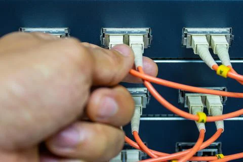 Technician connect fiber cable network to switch port in server room Photos