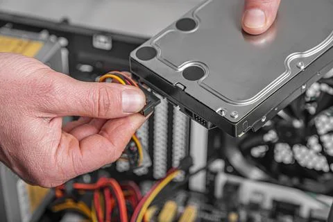 A technician connects a power cable to a hard disk drive. Stock Photos