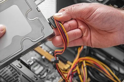 A technician connects a power cable to a hard drive. Stock Photos