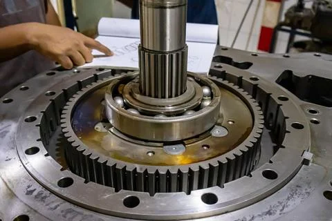 Technician consults manual while assembling transmission shaft and ball bea.. Stock Photos