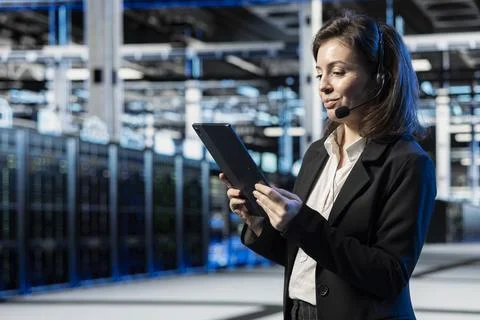 Technician in data center speaking into headset mic, managing support tickets Stockfoto's