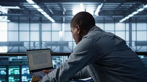 Technician in data center using programming languages on laptop Stock Photos