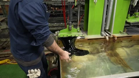 Technician dipping a finished black rubber boot into a shallow water bath to Stock Footage 342896902