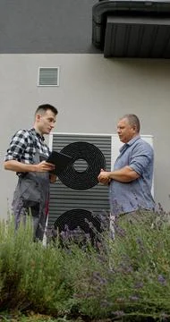 A technician discusses heat pump functionality with a homeowner in front of the 写真素材