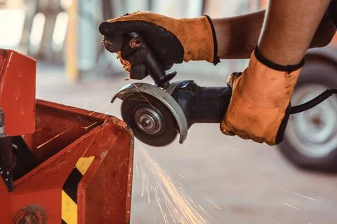 Technician with disk grinder working on farm machine Stock Photos