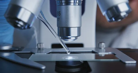Technician drips a solution from pipette on the glass slide for further Stock Footage 120729072