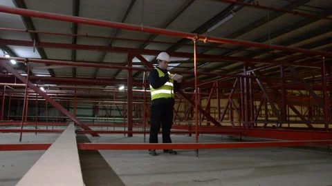 Technician engineer in a helmet checks the sprinklers pipes and roof constractio Видео 102934663