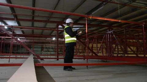 Technician engineer in a helmet checks the sprinklers pipes and roof constractio Видео 102935258