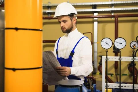 Technician engineer reads drawing on heating boiler station Stock Photos