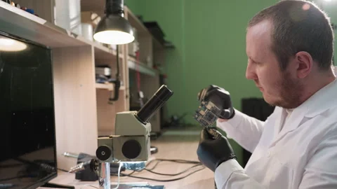 Technician Examining Circuit Board Under Microscope in Well-Lit Electronics Lab Video stock 285404606