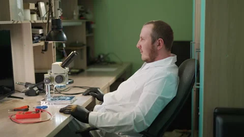 Technician Examining Circuit Under Microscope and Contemplating in Lab Stock Footage 282298730