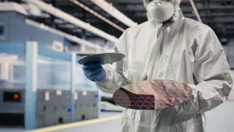 Technician examining semiconductor substrate in cleanroom of manufacturing plant Stock Footage 333394734