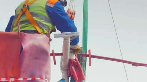 Technician fixes ceramic insulator red support on post against sky 库存影片 93339453