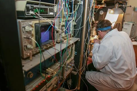 A technician is focused on fixing devices while surrounded by wires and machi Foto stock