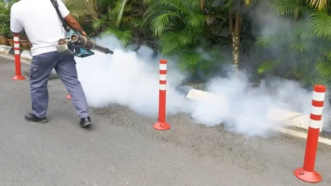 Technician fogging into drain to kill aedes mosquito, carrier of dengue and zika Stock Footage