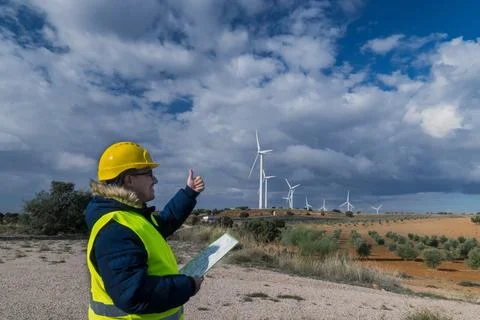 Technician gesturing thumbs up approving wind turbines in a wind farm Stock Photos