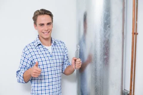 Technician gesturing thumbs up by hot water heater Stock Photos