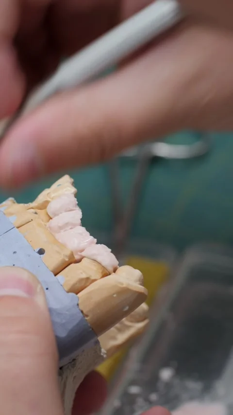 Technician hand marks edges of teeth on gypsum model with red color brush in lab Stock-Footage 328999988