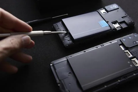 Technician hand using screwdriver for smartphone repair macro process Stock Photos