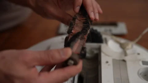 Technician hands cleaning tangled robot vacuum brush, performing detailed Stock Footage 304885022