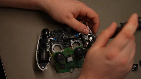 Technician hands using screwdriver working on gaming controller, revealing Stock Footage 307830587